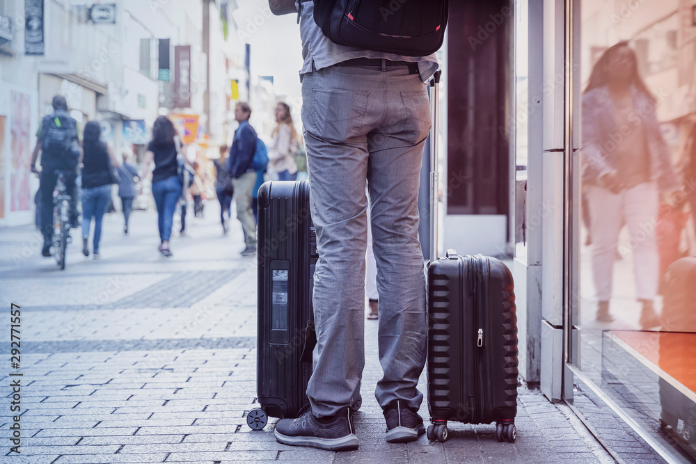 Fototapeta premium Unrecognizable young man traveling with suitcases, city street, travel and tourism concept