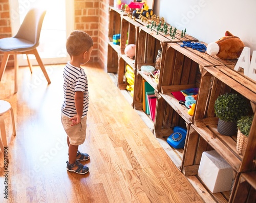 Beautiful toddler boy standing at kindergarten with lots of toys © Krakenimages.com