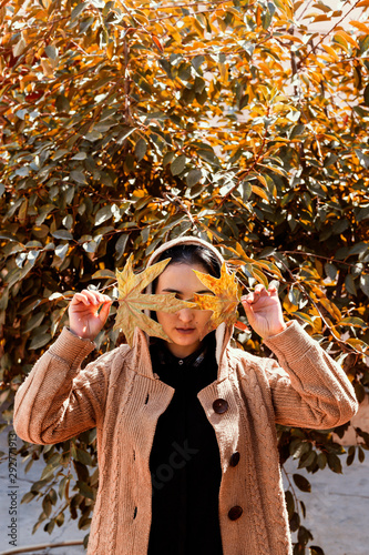 Fall season concept. Beautiful middle-eastern woman holds an yellow autumn leaf