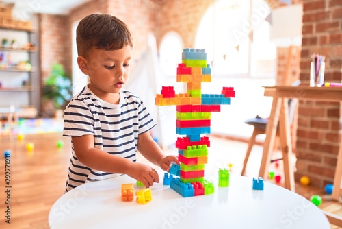 Beautiful toddler boy playing with construction blocks at kindergarten