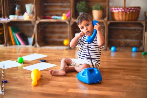 Beautiful toddler boy playing with vintage blue phone at kindergarten