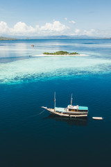 Deken met foto Blauw Luxury cruise boat sailing near coral reef atoll island with amazing white tropical beach and mountains on horizon. Aerial view. Luxury marine travel and vacations concept.  © Oleg Breslavtsev
