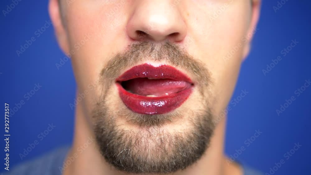 close-up. A bearded man with painted lips licks them sexually. close-up. A bearded man with painted lips licks them sexually.