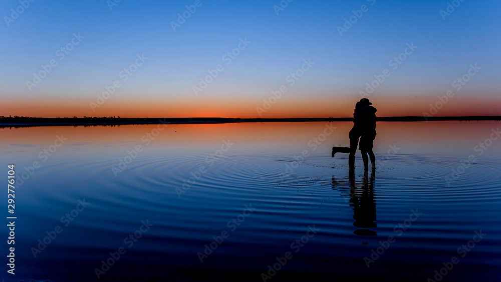Sihouette of man and woman hugging in watert at Lake Tyrrell at Sunset