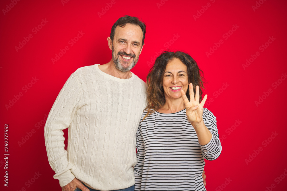 Beautiful middle age couple wearing winter sweater over isolated red background showing and pointing up with fingers number four while smiling confident and happy. Beautiful middle age couple wearing winter sweater over isolated red background showing and pointing up with fingers number four while smiling confident and happy.