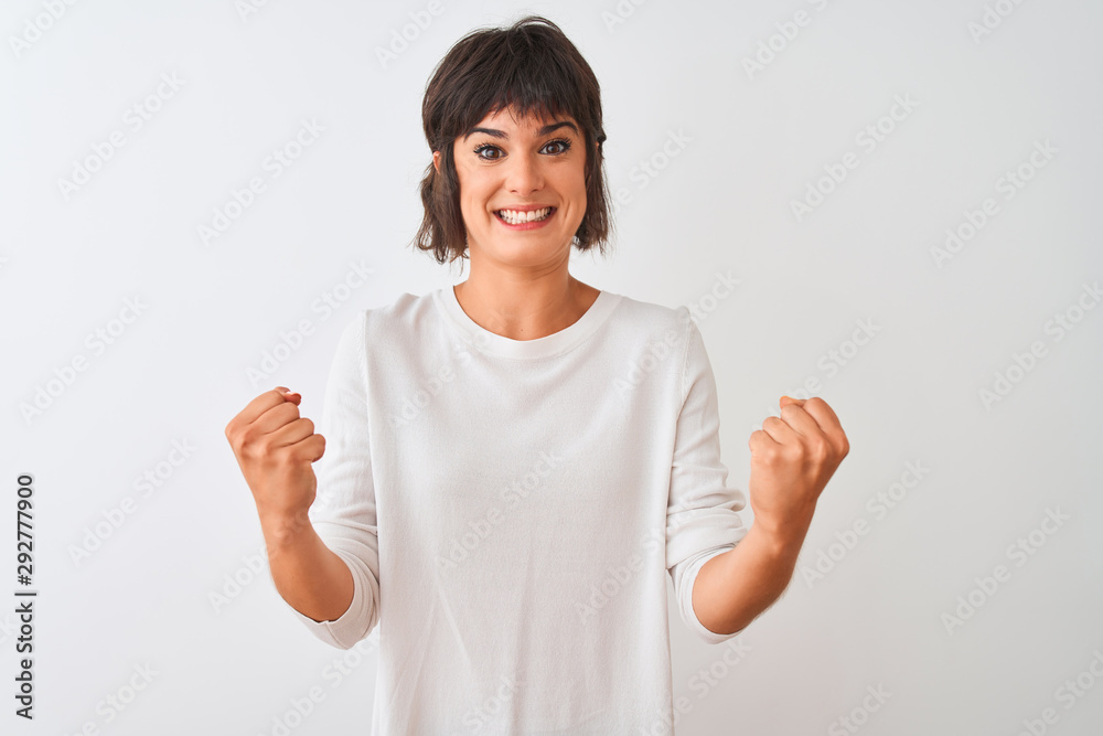 Young beautiful woman wearing casual t-shirt standing over isolated white background celebrating surprised and amazed for success with arms raised and open eyes. Winner concept. Young beautiful woman wearing casual t-shirt standing over isolated white background celebrating surprised and amazed for success with arms raised and open eyes. Winner concept.