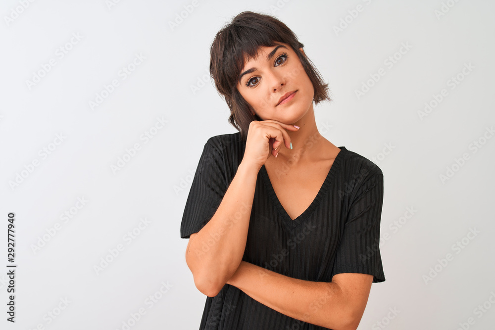 Young beautiful woman wearing black t-shirt standing over isolated white background with hand on chin thinking about question, pensive expression. Smiling with thoughtful face. Doubt concept. Young beautiful woman wearing black t-shirt standing over isolated white background with hand on chin thinking about question, pensive expression. Smiling with thoughtful face. Doubt concept.
