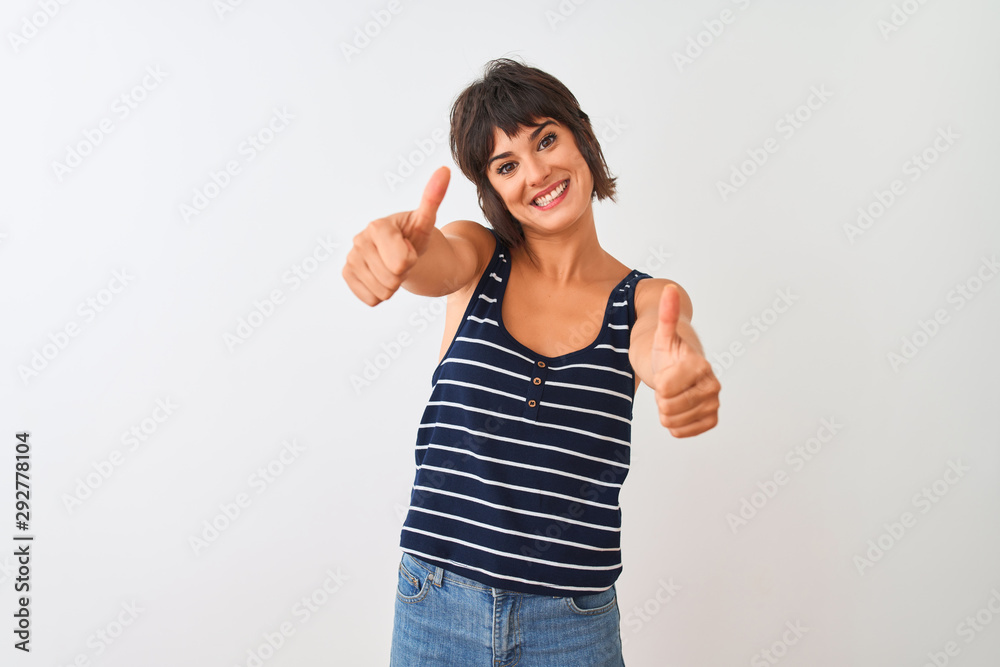 Young beautiful woman wearing striped t-shirt standing over isolated white background approving doing positive gesture with hand, thumbs up smiling and happy for success. Winner gesture. Young beautiful woman wearing striped t-shirt standing over isolated white background approving doing positive gesture with hand, thumbs up smiling and happy for success. Winner gesture.