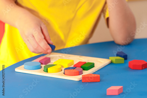 Kid playing with wooden colorful puzzle, education concept