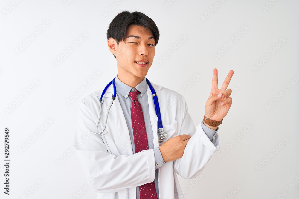 Chinese doctor man wearing coat tie and stethoscope over isolated white background smiling with happy face winking at the camera doing victory sign. Number two. Chinese doctor man wearing coat tie and stethoscope over isolated white background smiling with happy face winking at the camera doing victory sign. Number two.