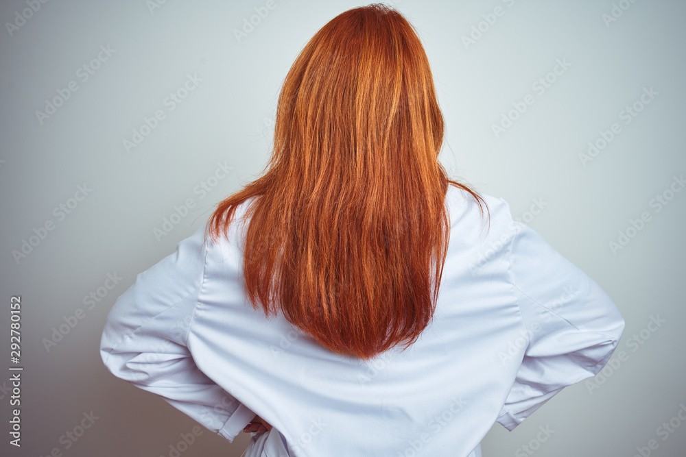 Young redhead doctor woman using stethoscope over white isolated background standing backwards looking away with arms on body Young redhead doctor woman using stethoscope over white isolated background standing backwards looking away with arms on body