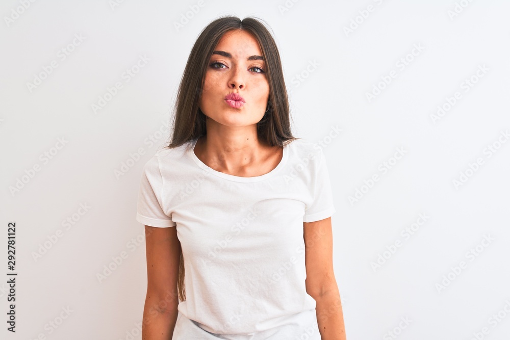 Young beautiful woman wearing casual t-shirt standing over isolated white background looking at the camera blowing a kiss on air being lovely and sexy. Love expression. Young beautiful woman wearing casual t-shirt standing over isolated white background looking at the camera blowing a kiss on air being lovely and sexy. Love expression.