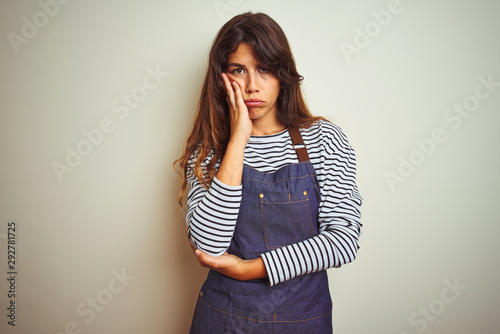 Young beautiful chef woman wearing apron cooking over white isolated background thinking looking tired and bored with depression problems with crossed arms. © Krakenimages.com