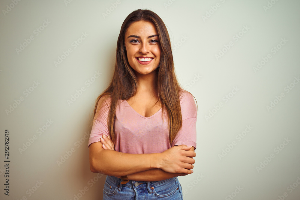Fototapeta premium Young beautiful woman wearing casual t-shirt standing over isolated white background happy face smiling with crossed arms looking at the camera. Positive person.