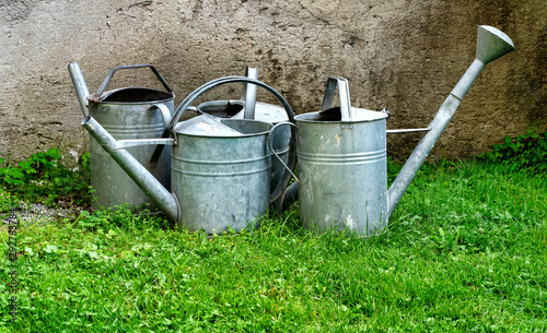 Old sheet metal watering cans on grass
