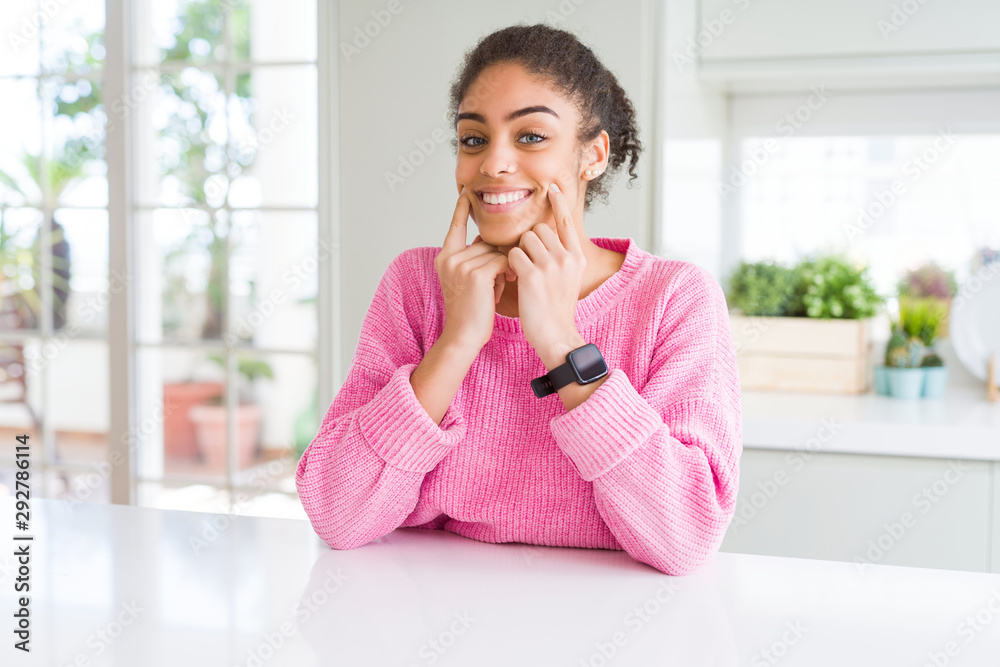 Beautiful african american woman with afro hair wearing casual pink sweater Smiling with open mouth, fingers pointing and forcing cheerful smile Beautiful african american woman with afro hair wearing casual pink sweater Smiling with open mouth, fingers pointing and forcing cheerful smile