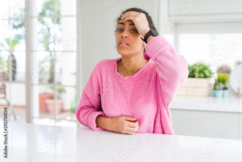 Beautiful african american woman with afro hair wearing casual pink sweater Touching forehead for illness and fever, flu and cold, virus sick