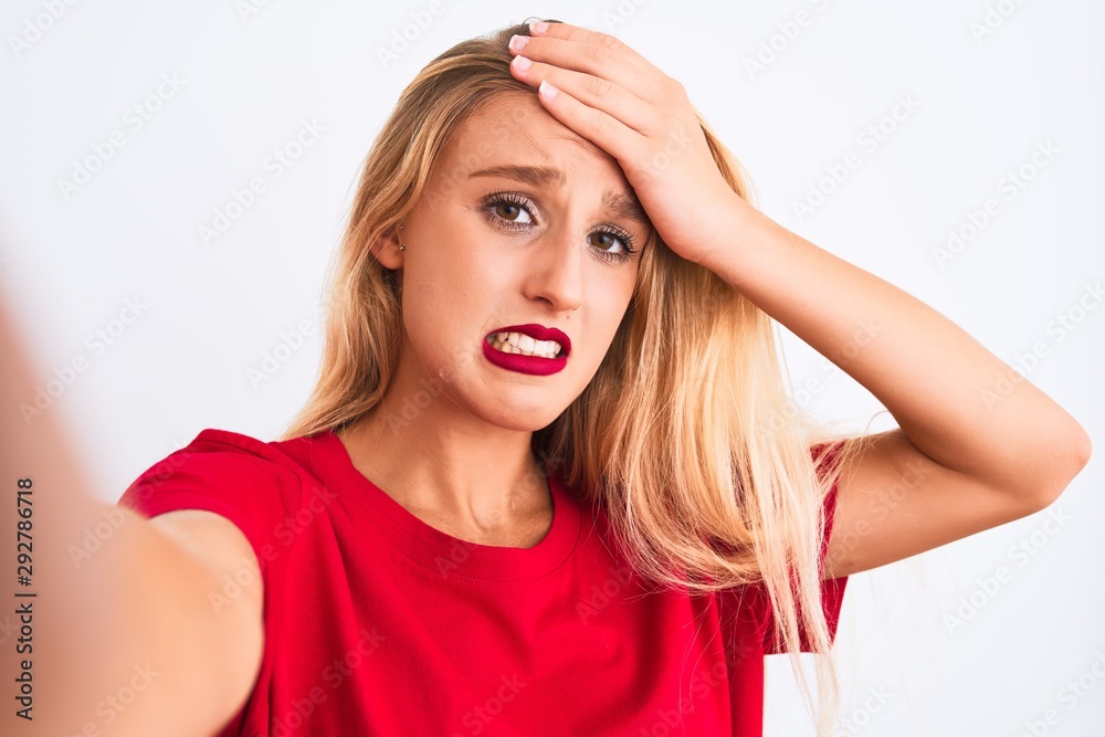 Young beautiful woman wearing t-shirt make selfie by camera over isolated white background stressed with hand on head, shocked with shame and surprise face, angry and frustrated. Fear and upset Young beautiful woman wearing t-shirt make selfie by camera over isolated white background stressed with hand on head, shocked with shame and surprise face, angry and frustrated. Fear and upset