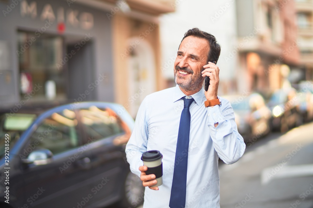 Middle age handsome businessman talking on the smartphone drinking take away coffee smiling Middle age handsome businessman talking on the smartphone drinking take away coffee smiling