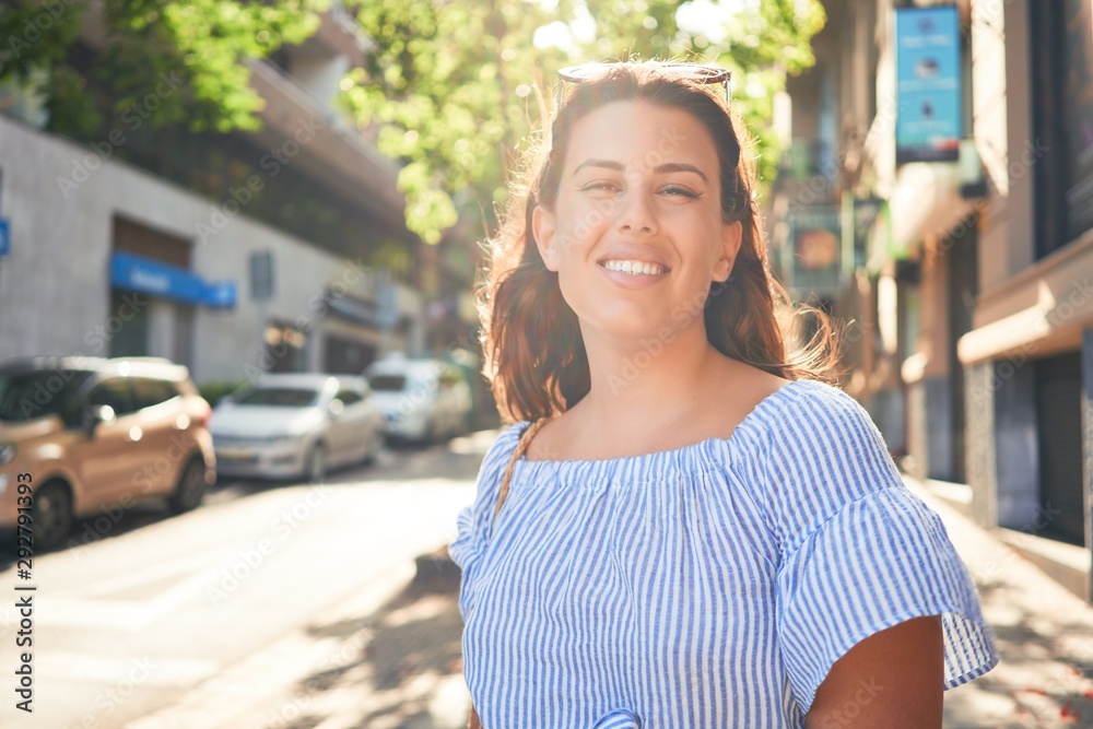 Young beautiful woman smiling happy walking on city streets on a sunny day of summer