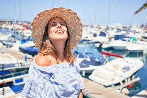 Young beautiful woman at marine port around boats, smiling happy with seaport at the background © Krakenimages.com