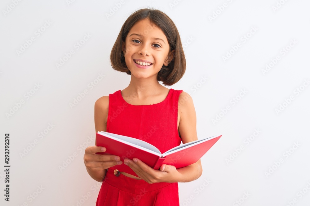 Beautiful student child girl reading red book standing over isolated white background with a happy face standing and smiling with a confident smile showing teeth