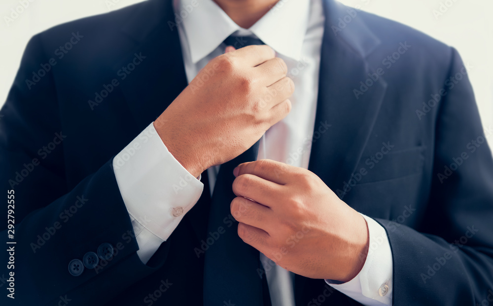 Businessman in black suit and adjusting necktie.