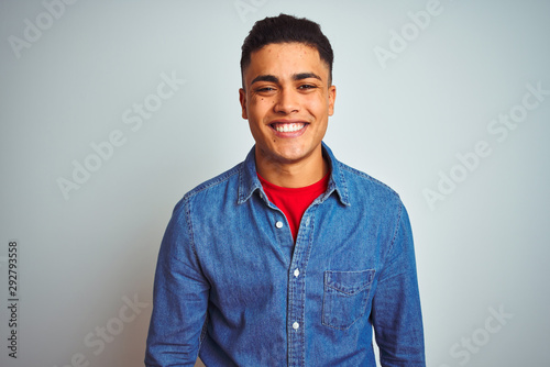 Young brazilian man wearing denim shirt standing over isolated white background with a happy and cool smile on face. Lucky person.