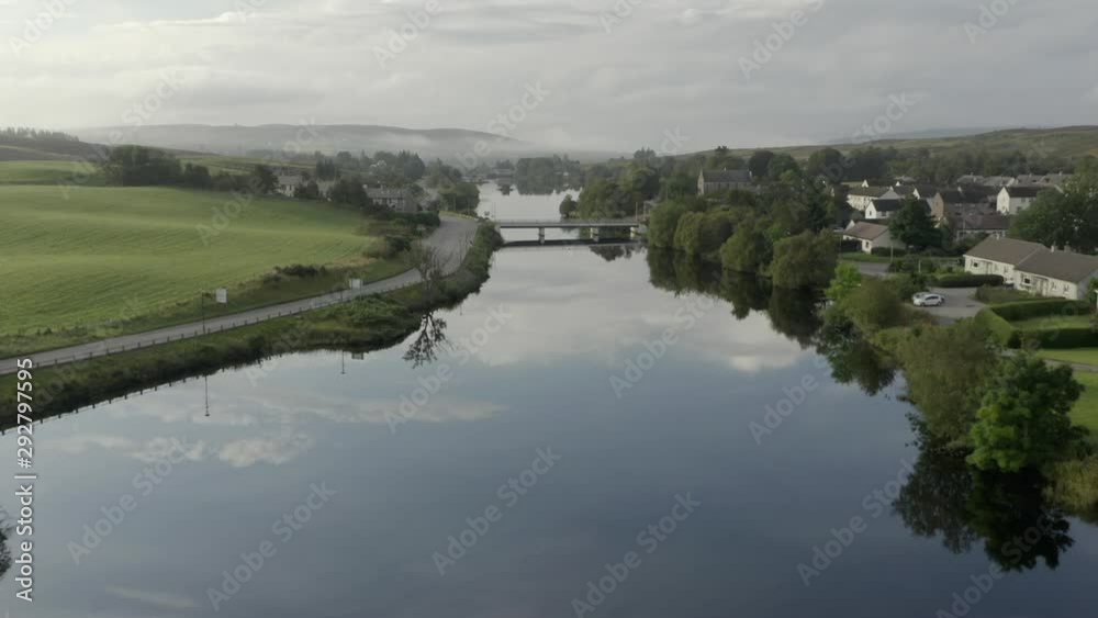 An aerial view of the River Shin at Lairg on a calm and misty summer's moring. Flying over the river towards a bridge while zooming in. An aerial view of the River Shin at Lairg on a calm and misty summer's moring. Flying over the river towards a bridge while zooming in.