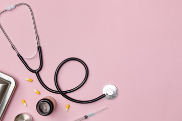 Creative flatlay of doctor medical equipment pink table with stethoscope, medical documents, thermometer, syringe and pills, Health care concept, Top view with copy space, Isolated on pink