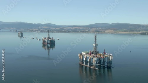 An aerial view of three oil rigs on the Cromarty Firth on a sunny summer's day. Rotating anti-clockwise around the rigs.
