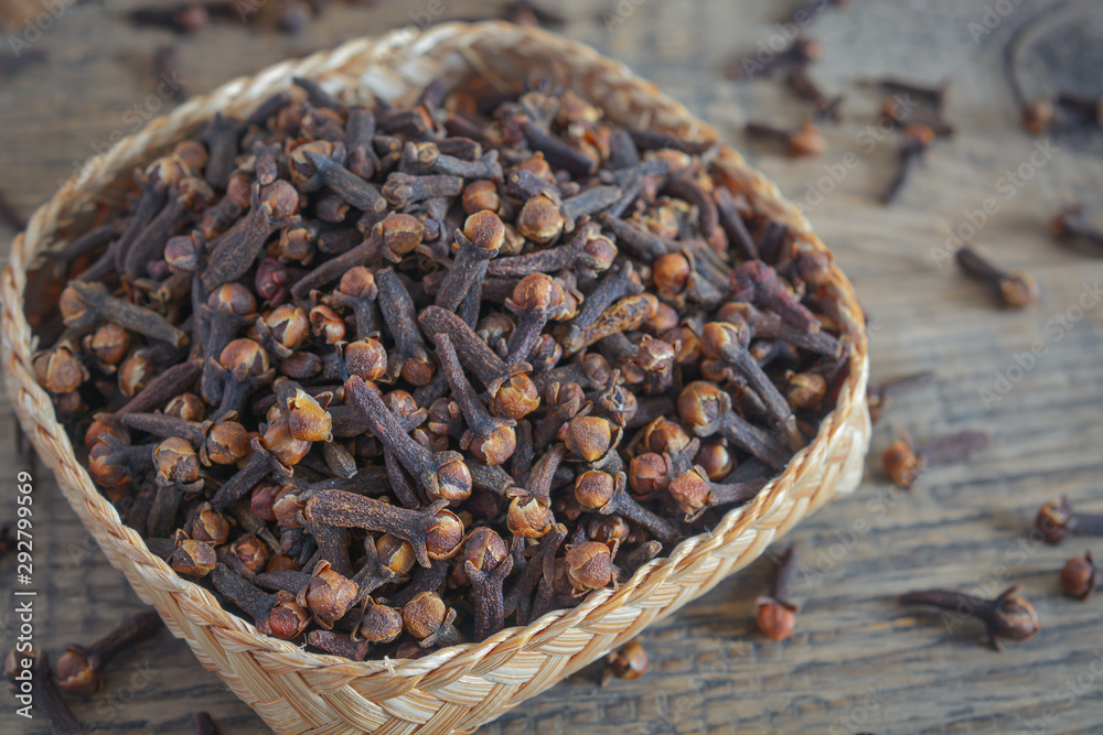 dried cloves on hand made bamboo wood bowl and wooden background. dried cloves on hand made bamboo wood bowl and wooden background.