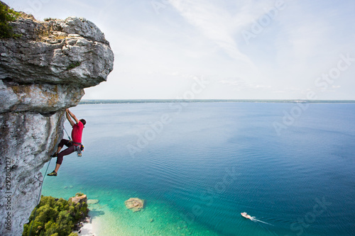 Rock climbing a steep cliff high above a large lake.