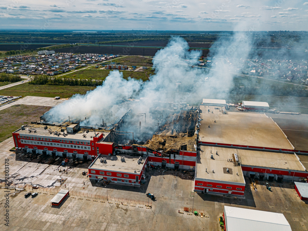 Fototapeta premium Burning industrial distribution warehouse, aerial drone view