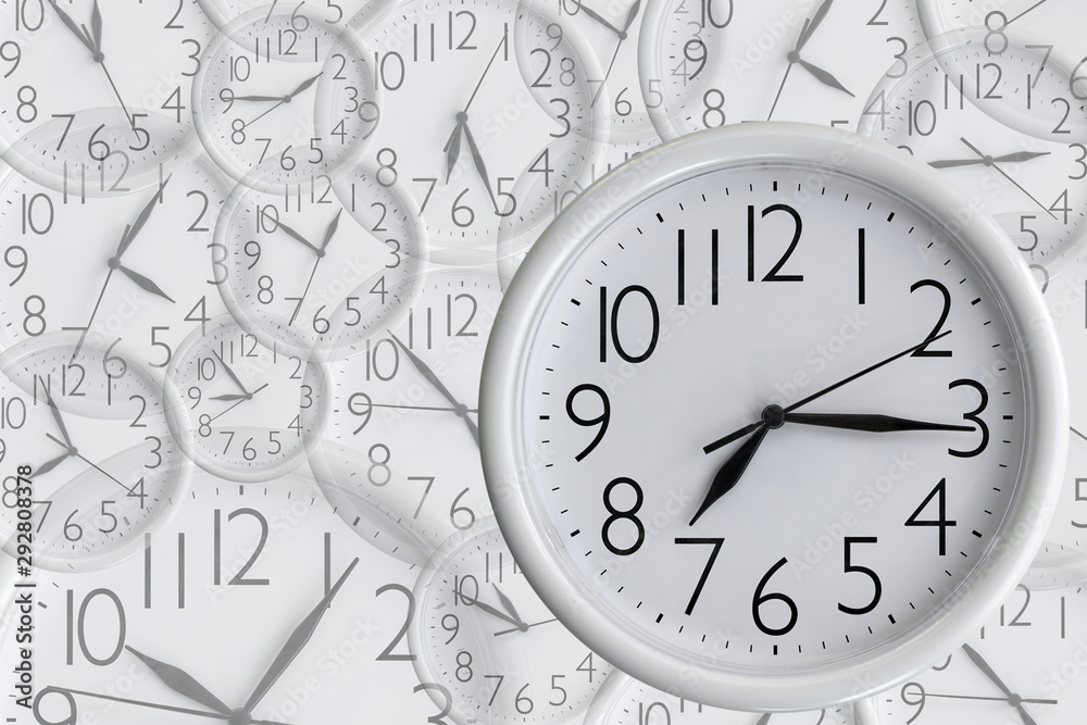 White analog round office clock on the background of a set of clocks f different sizes showing various time White analog round office clock on the background of a set of clocks f different sizes showing various time