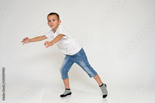 Full-length portrait on a white background of a cute boy child with Vitiligo disease - a violation of the color of the skin at the initial stage. White T-shirt, blue jeans.