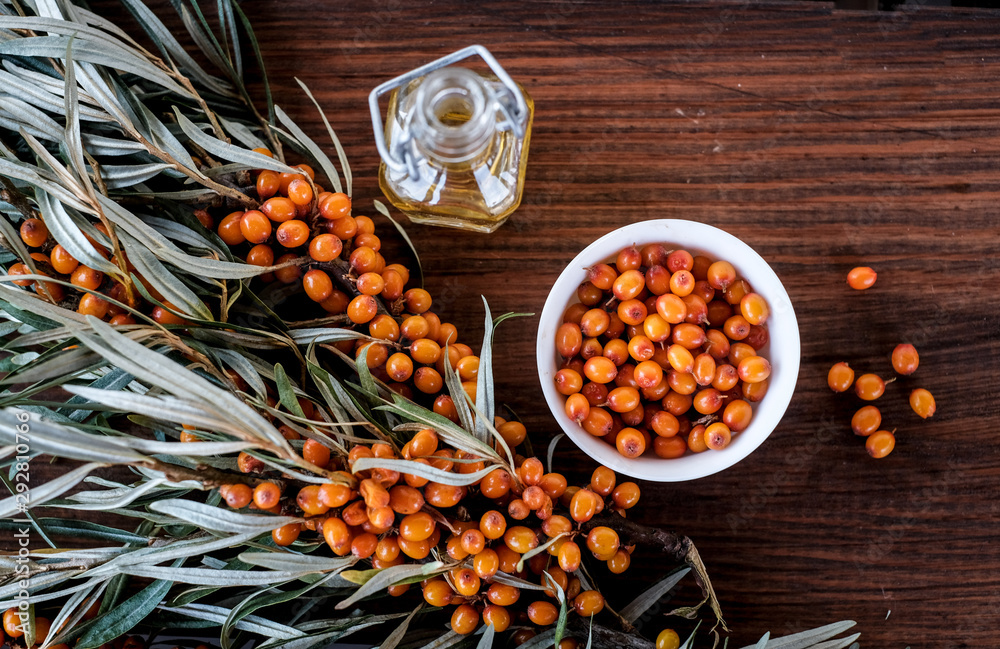 Leaves and berries of orange sea buckthorn on wooden table background Leaves and berries of orange sea buckthorn on wooden table background
