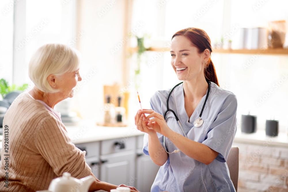 Young nurse laughing before making injection Young nurse laughing before making injection
