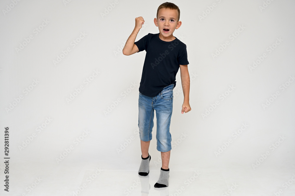 Full-length portrait on a white background of a cute boy child with Vitiligo disease - a violation of the color of the skin at the initial stage. Black T-shirt, blue jeans. Full-length portrait on a white background of a cute boy child with Vitiligo disease - a violation of the color of the skin at the initial stage. Black T-shirt, blue jeans.