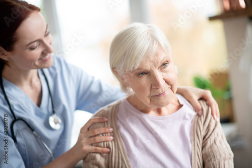 Smiling caregiver doing massage for retired woman