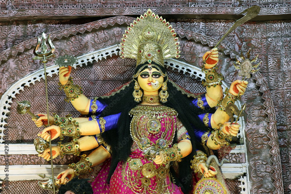 Goddess Durga idol at decorated Durga Puja pandal, shot at colored light, at Kolkata, West Bengal, India. Durga Puja is biggest religious festival of Hinduism and is now celebrated worldwide.