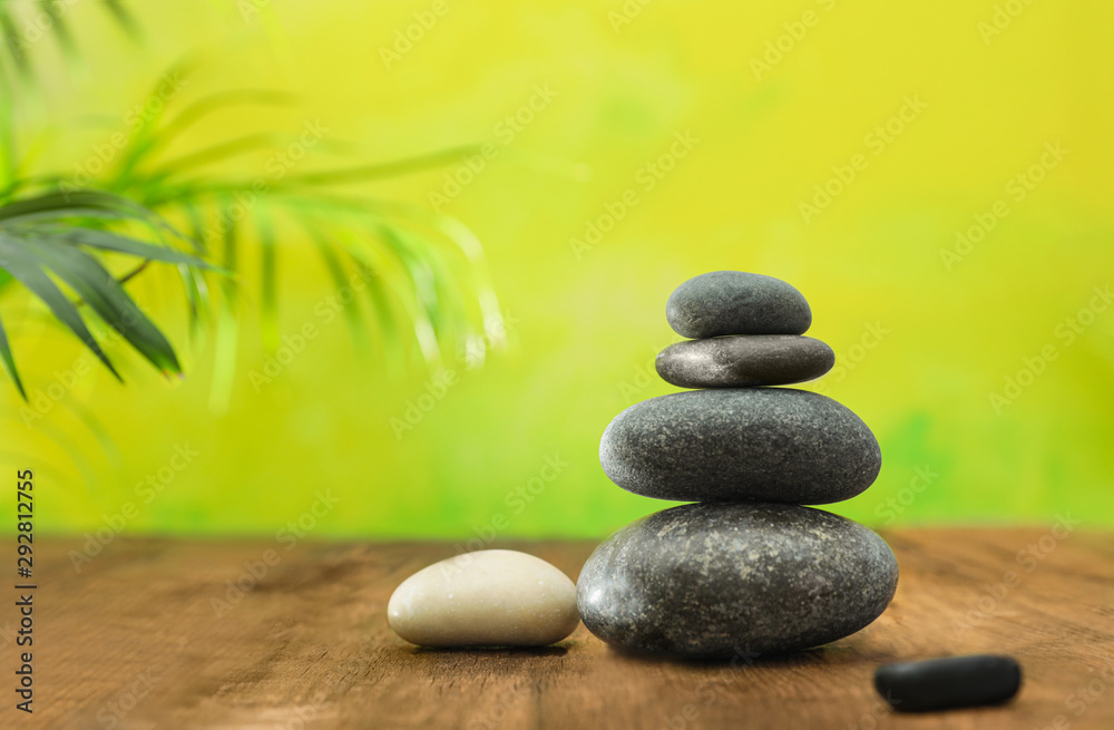 Table with stack of stones and blurred green leaves on background, space for text. Zen concept Table with stack of stones and blurred green leaves on background, space for text. Zen concept