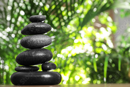 Stack of stones and blurred green leaves on background  space for text. Zen concept
