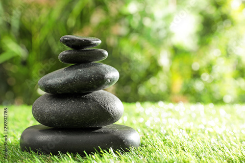 Stack of stones on green grass against blurred background  space for text. Zen concept