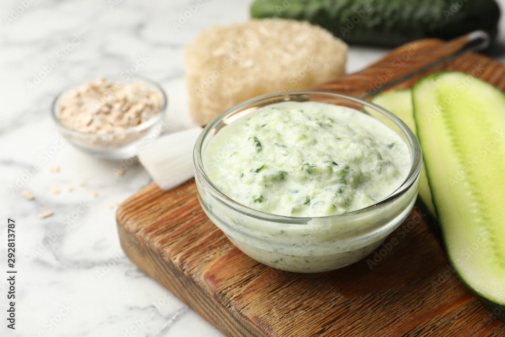 Handmade cucumber face mask in glass bowl and ingredients on marble table Handmade cucumber face mask in glass bowl and ingredients on marble table