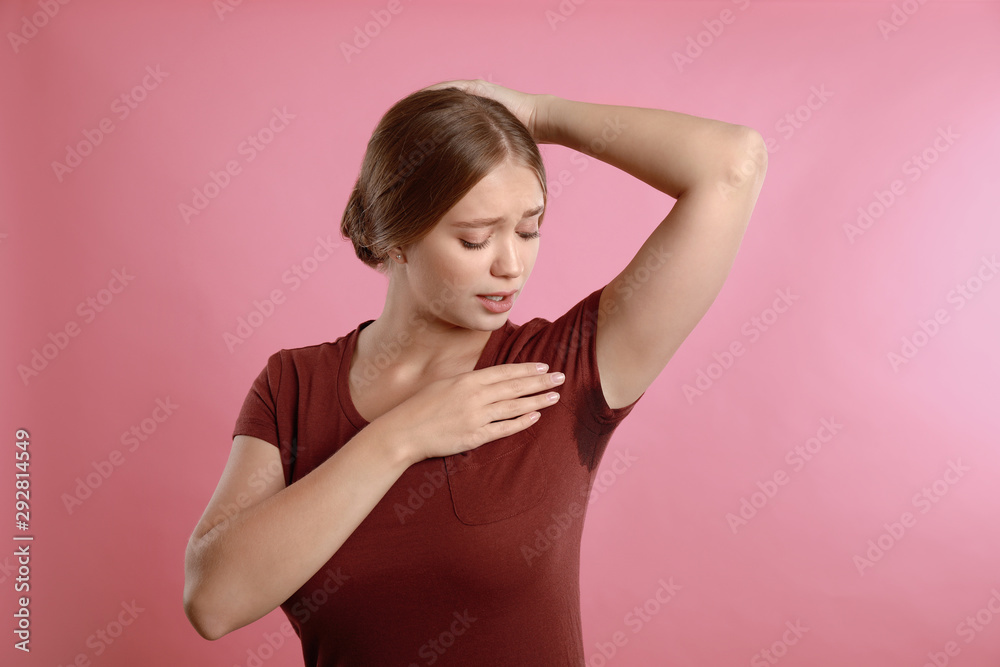 Young woman with sweat stain on her clothes against pink background. Using deodorant Young woman with sweat stain on her clothes against pink background. Using deodorant