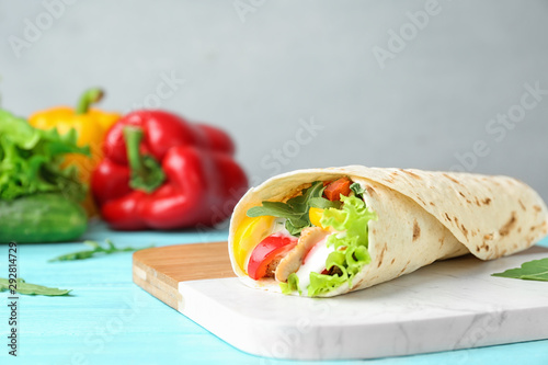 Delicious meat tortilla wrap on blue wooden table, space for text