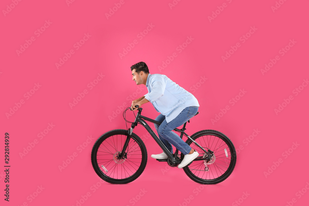 Handsome young man with modern bicycle on pink background Handsome young man with modern bicycle on pink background