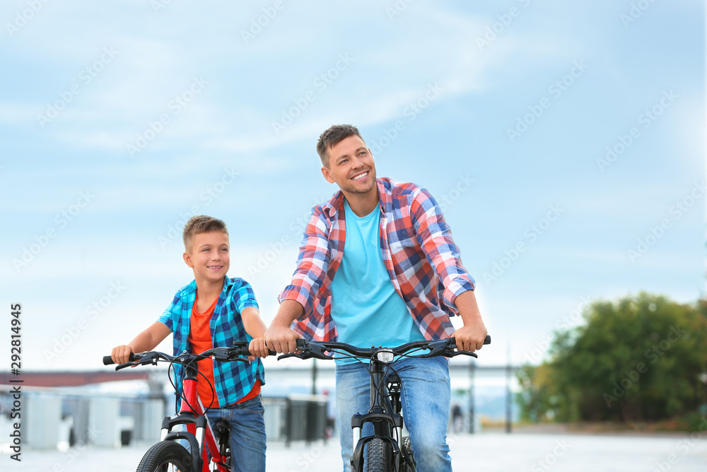 Dad and son riding bicycles together outdoors Dad and son riding bicycles together outdoors