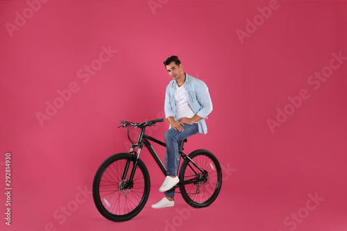 Fototapeta Naklejka Na Ścianę i Meble -  Handsome young man with modern bicycle on pink background